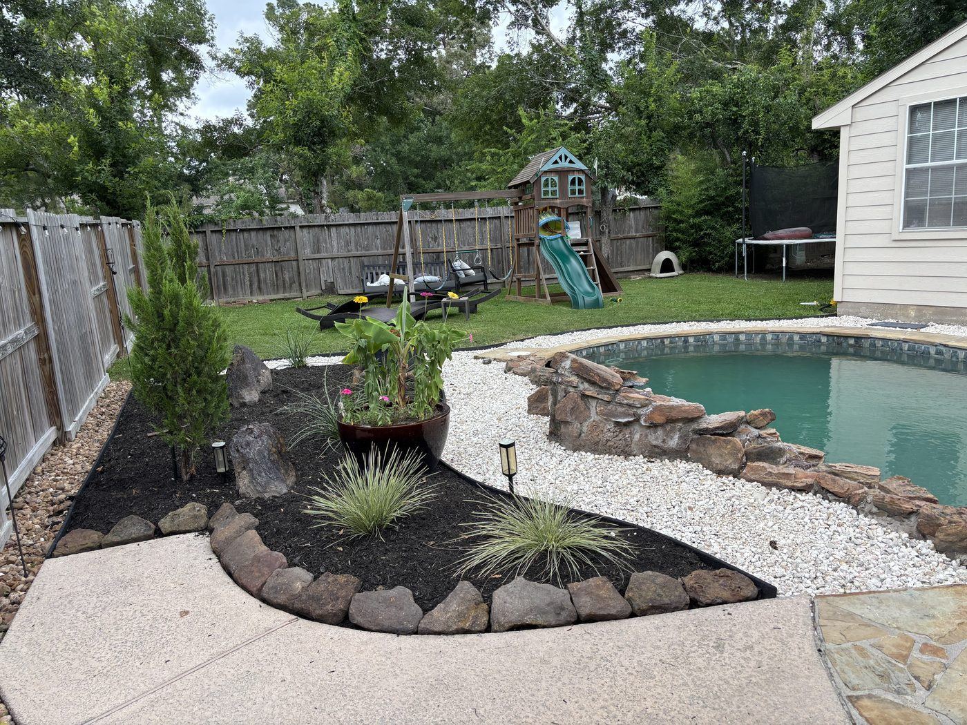 Poolside landscape planting bed with rock edging Houston TX